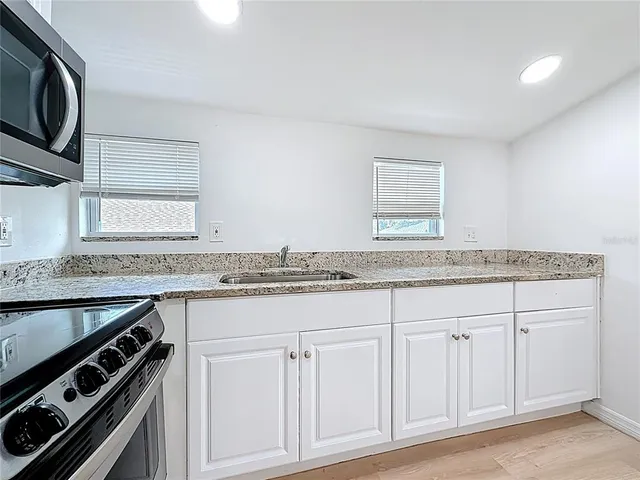 a kitchen with granite countertop a sink stove and cabinets