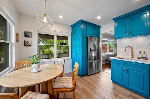 a kitchen with stainless steel appliances wooden floor dining table and chairs