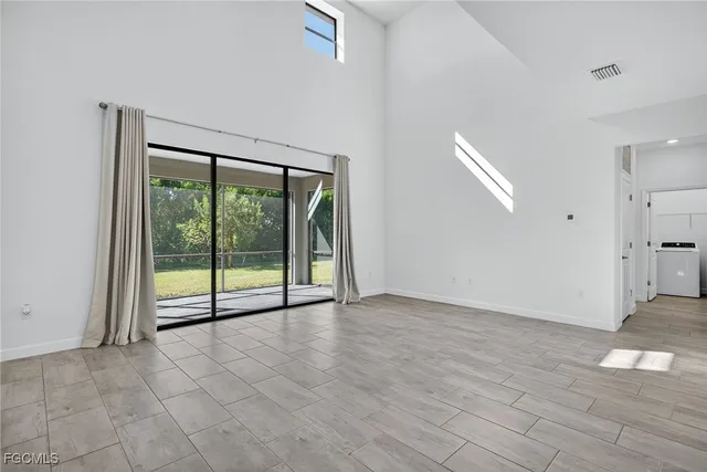 a view of an empty room with wooden floor and door