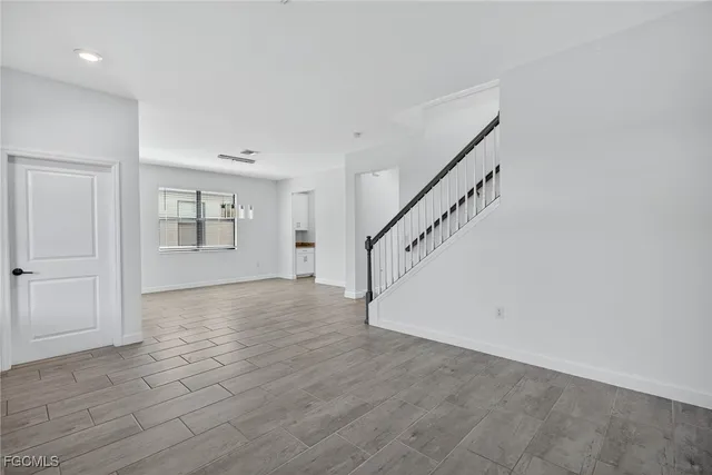a view of an empty room with wooden floor and entryway