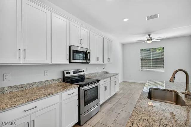 a kitchen with granite countertop a sink and white cabinets