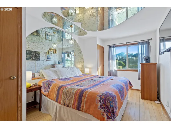 a bedroom with a bed a window and painting on the wall