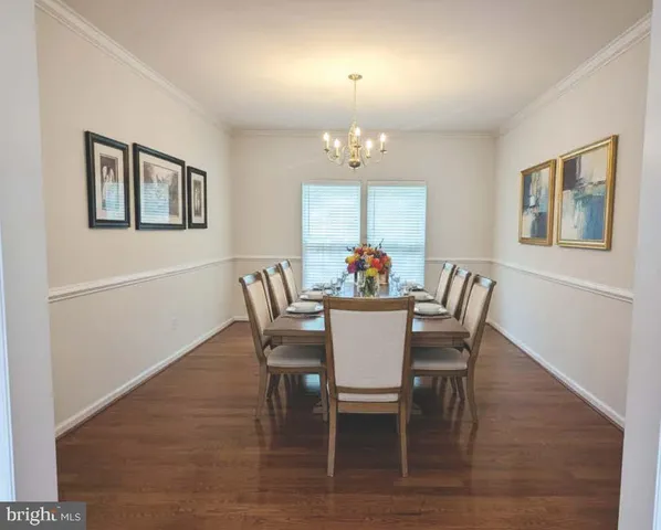 an empty room with wooden floor chandelier and windows