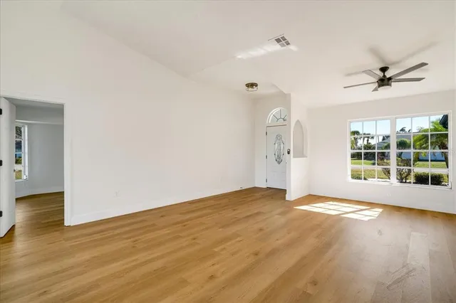 a view of empty room with wooden floor and fan