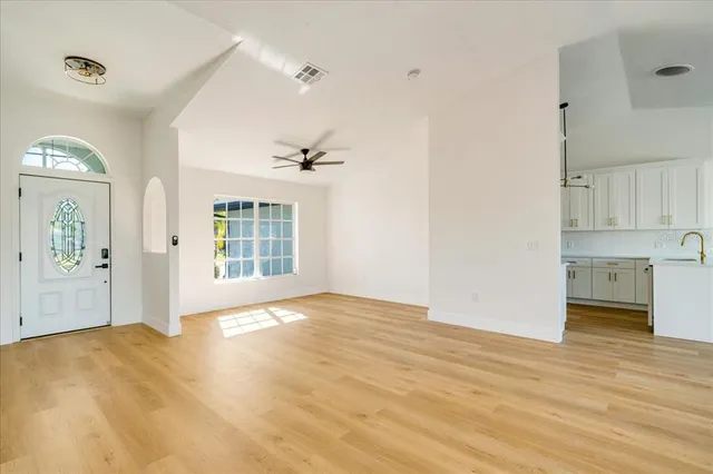a view of an empty room with a window and wooden floor