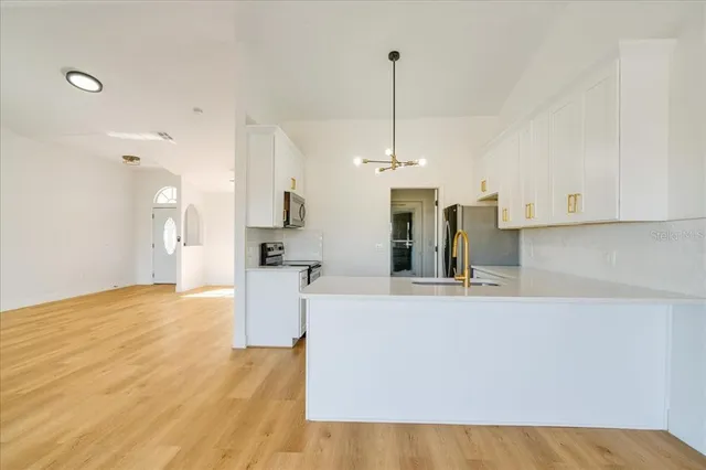 a view of a kitchen with kitchen island white cabinets and stainless steel appliances