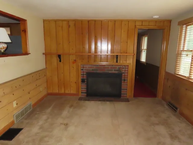 a view of an empty room with wooden floor and a fireplace