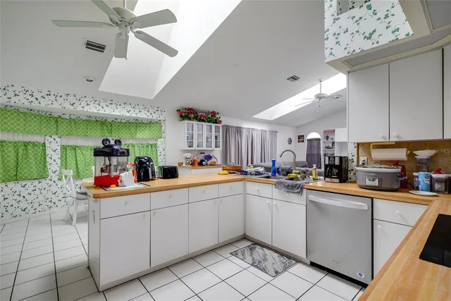 a living room with couches a chandelier and kitchen view