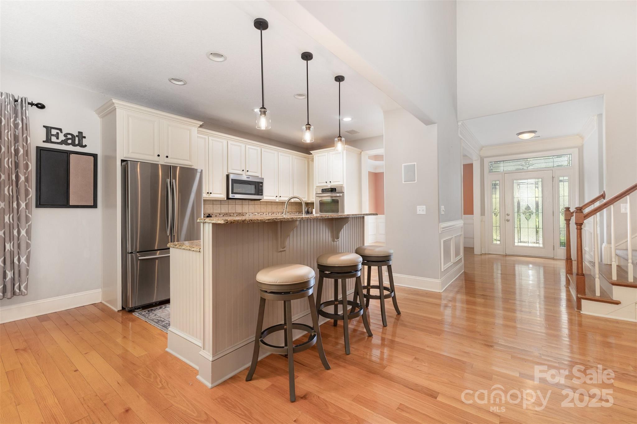 689 Presbyterian Road Mooresville, NC 28115 - Photo 6 of 34 a kitchen with stainless steel appliances a refrigerator a stove a sink a dining table and chairs with wooden floor