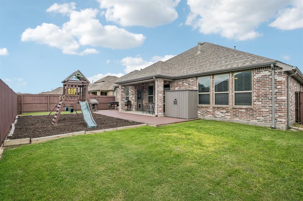 1805 Huntsman Way Forney, TX 75126 - Photo 33 of 34 Expansive rear yard featuring a covered patio, brick exterior, fenced perimeter, and established lawn
