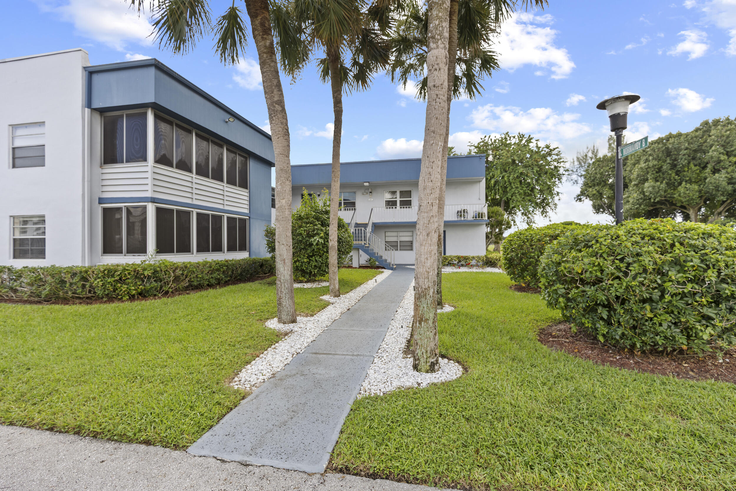74 Normandy B Delray Beach, FL 33484 - Photo 19 of 21 a front view of a house with a yard and palm trees