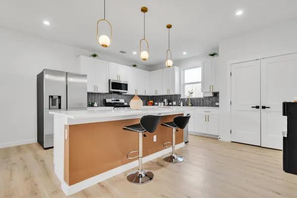 a kitchen with stainless steel appliances granite countertop a stove a sink dishwasher and a refrigerator with wooden floor
