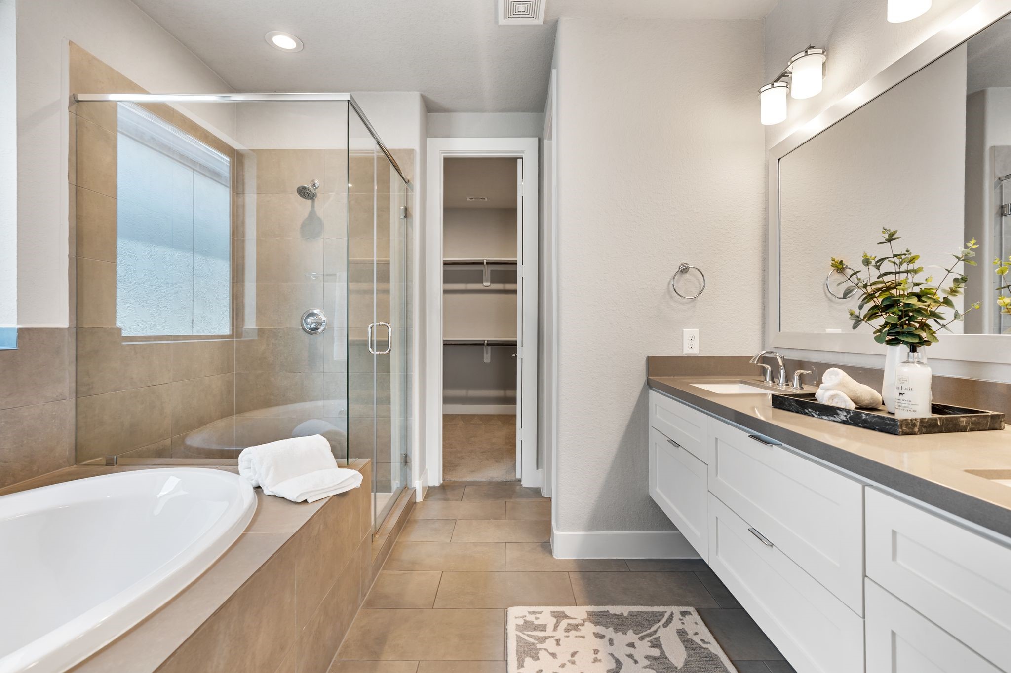 4219 Allen Street Houston, TX 77007 - Photo 18 of 29 Double doors open to a spa-like retreat featuring a floating vanity with dual sinks, quartz countertops, and a large decorative mirror with vanity lighting. A separate water closet adds privacy, while the huge walk-in closet offers exceptional storage.Indulge in the soaking tub with tile surround or the walk-in shower with frameless glass enclosure.