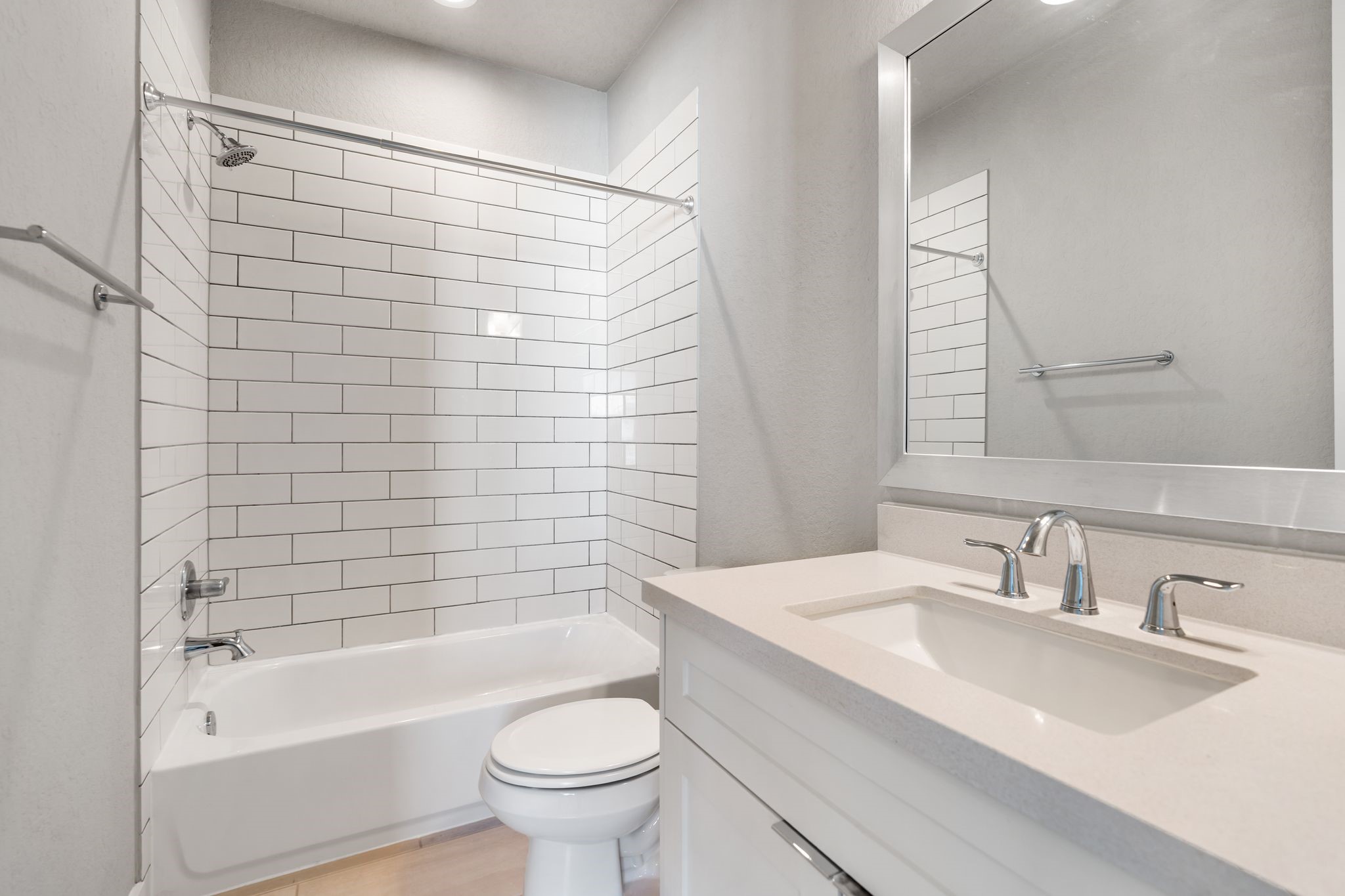 4219 Allen Street Houston, TX 77007 - Photo 20 of 29 Ensuite Bathroom includes a vanity with quartz countertop and storage, decorative mirror, vanity lighting, and a tub/shower combination with subway tile surround.