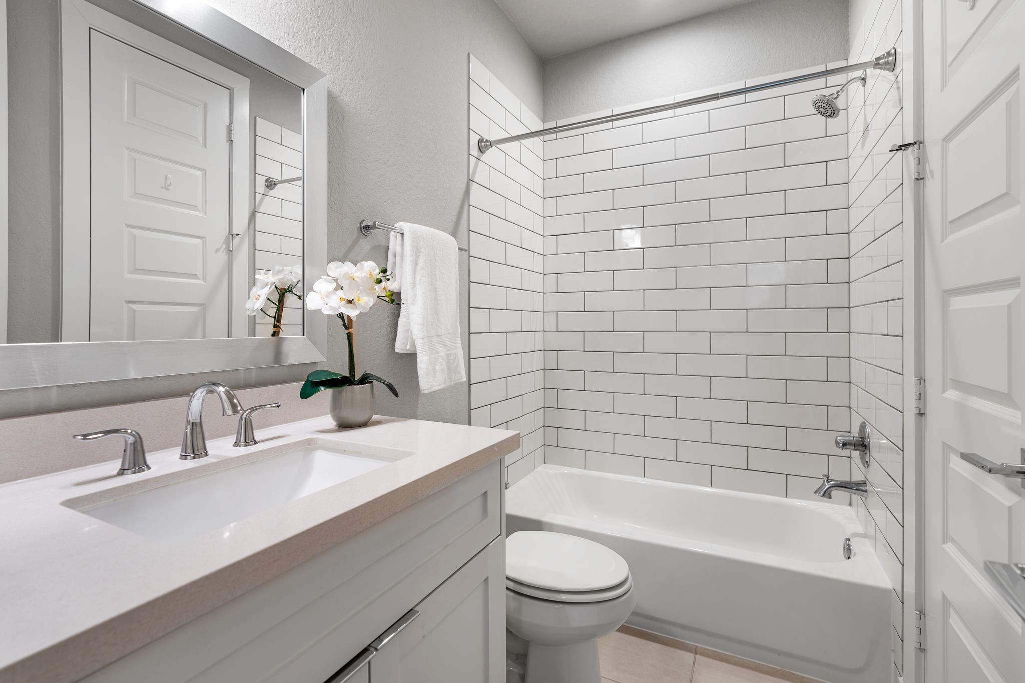 4219 Allen Street Houston, TX 77007 - Photo 22 of 29 Ensuite Bathroom features a vanity with quartz countertop and storage, decorative mirror, vanity lighting, and a tub/shower combination with white subway tile surround.