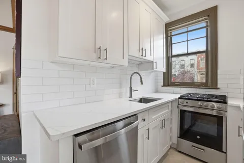 a kitchen with white cabinets appliances and sink