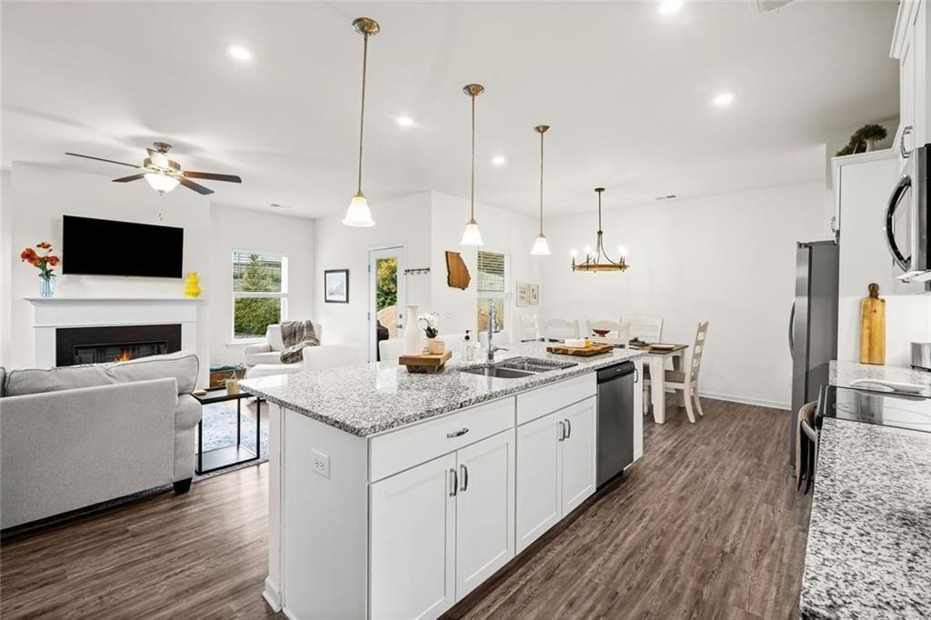 252 Renford Road Ball Ground, GA 30107 - Photo 5 of 36 a open kitchen with stainless steel appliances granite countertop a stove top oven a sink dishwasher and a fireplace with wooden floor