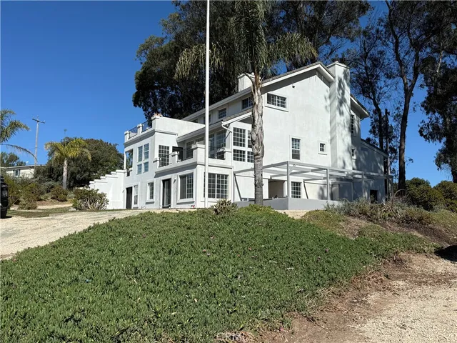 a view of white house with a yard and potted plants