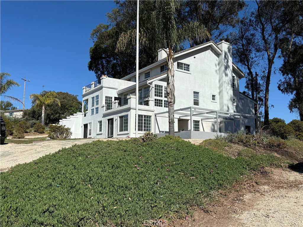a view of white house with a yard and potted plants