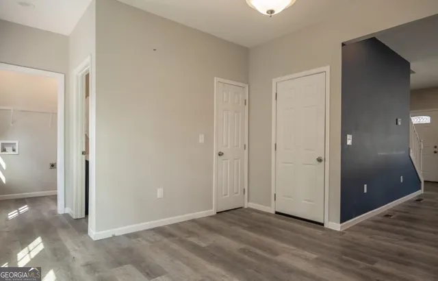 a view of an empty room with wooden floor and a bathroom