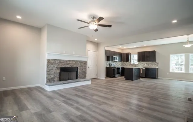 a view of a kitchen with a stove a fireplace a ceiling fan and wooden floor