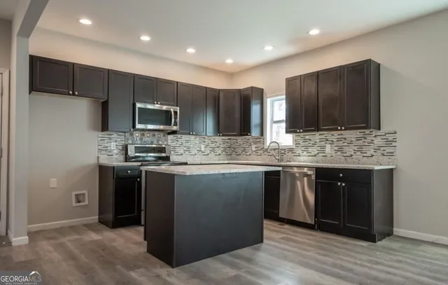 a kitchen with stainless steel appliances granite countertop a refrigerator and a stove top oven
