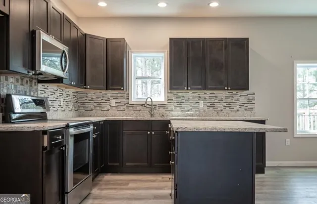 a kitchen with stainless steel appliances granite countertop a sink stove and microwave