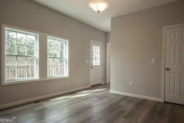 an empty room with wooden floor and windows