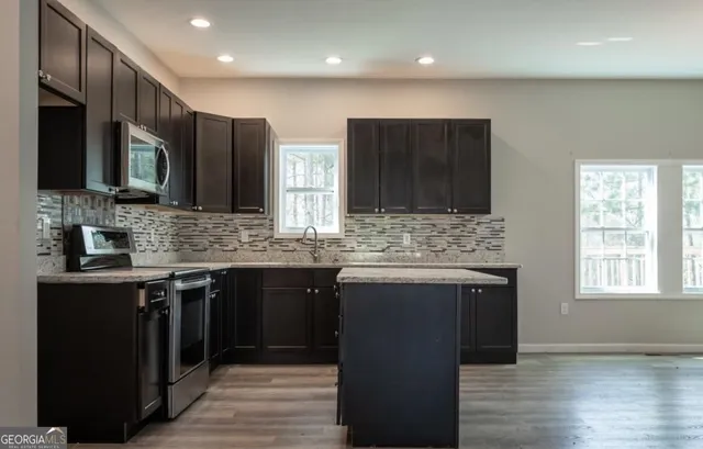 a kitchen with stainless steel appliances granite countertop a sink stove and cabinets