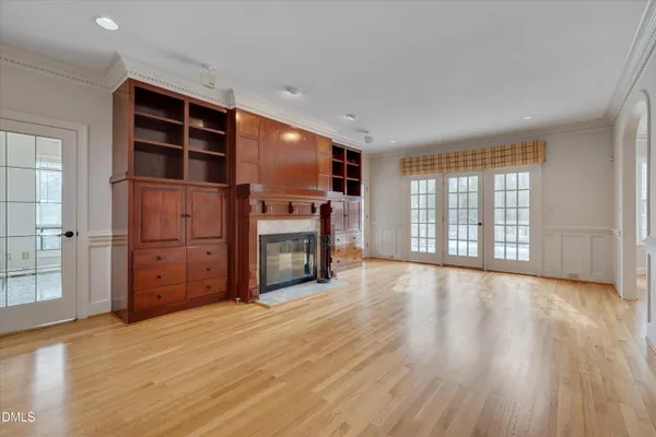 a view of an empty room with wooden floor fireplace and a window