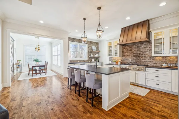 a kitchen with stainless steel appliances granite countertop a stove refrigerator a oven a sink with a dining table and chairs