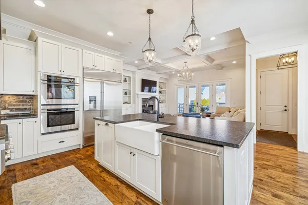 a large kitchen with granite countertop lots of white cabinets appliances and furniture
