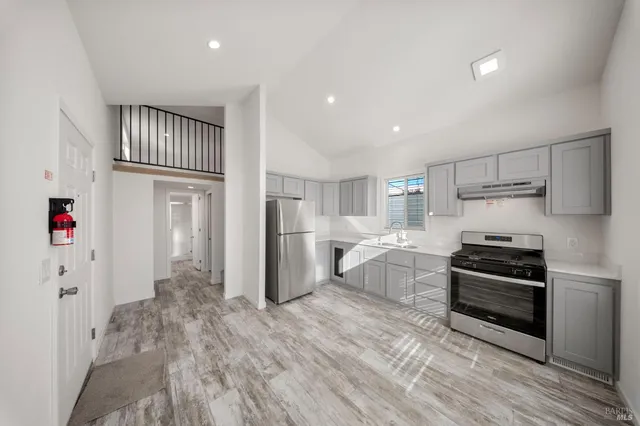 a kitchen with granite countertop a refrigerator and a stove top oven