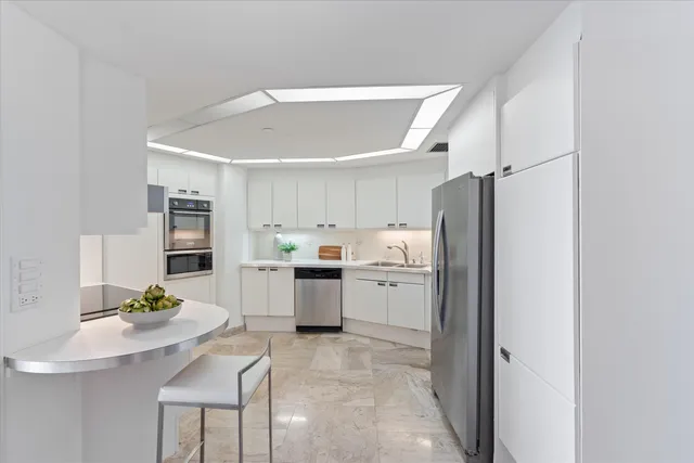 a kitchen that has a refrigerator a sink a stove and chairs