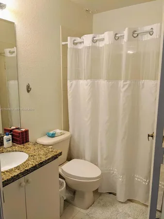 a bathroom with a granite countertop sink toilet and shower