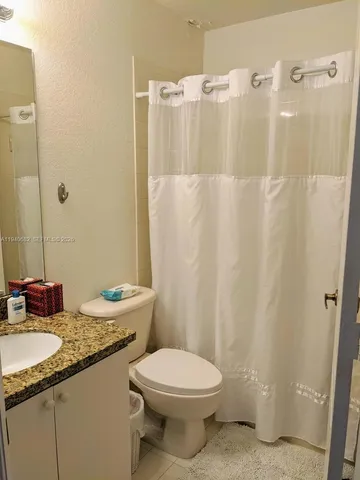 a bathroom with a granite countertop sink toilet and shower