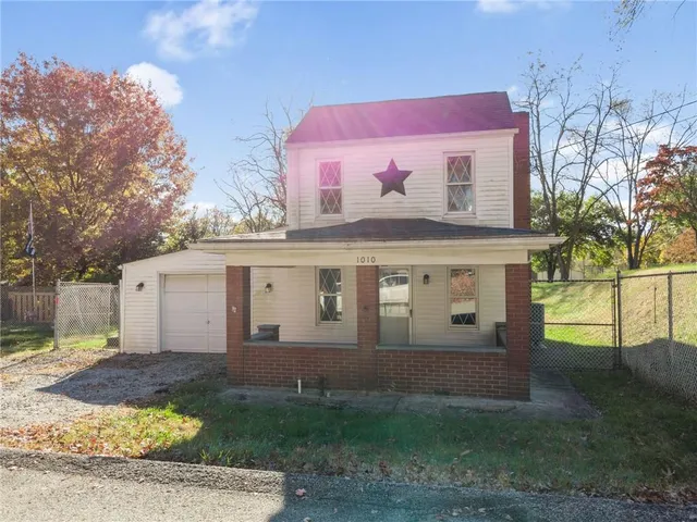 a view of a white house next to a yard with big trees