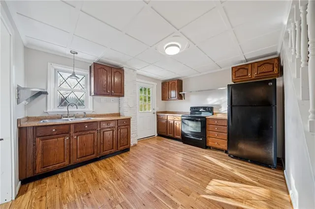 a kitchen with granite countertop stainless steel appliances a refrigerator cabinets and wooden floor