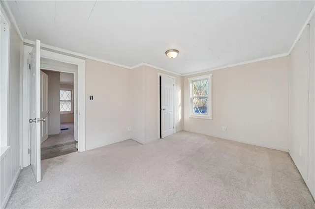 a view of an empty room with closet and a window