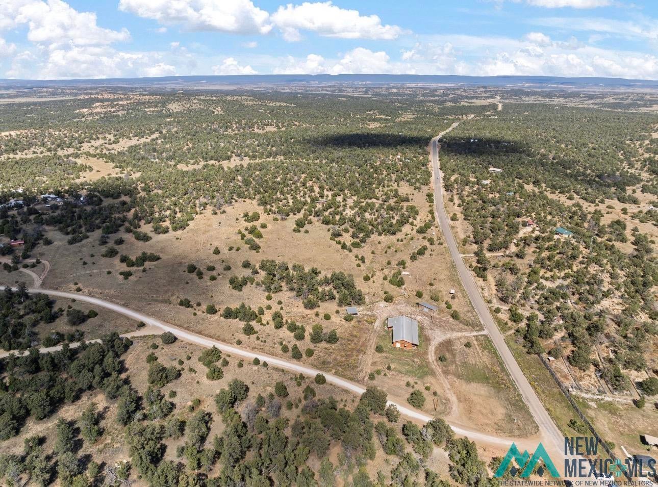 371 Candy Kitchen Road Candy Kitchen, NM 87357 - Photo 32 of 49 Expansive natural landscape featuring a single-story building with a silver-toned metal roof, a paved road, and unpaved roads