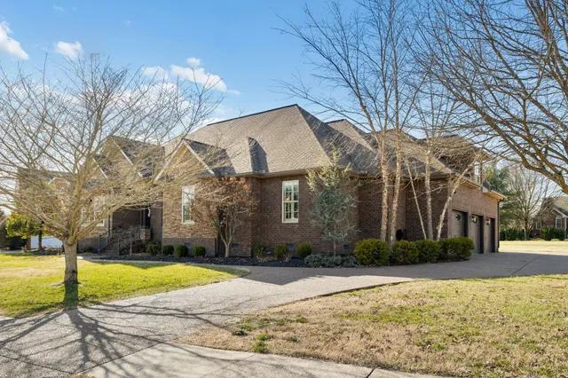 a view of a house with a yard and large tree