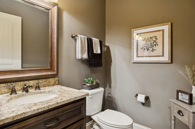 a bathroom with a granite countertop toilet sink and mirror
