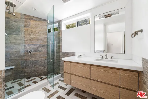 a bathroom with a sink and mirror with shower