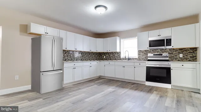 a kitchen with granite countertop a refrigerator stove and sink