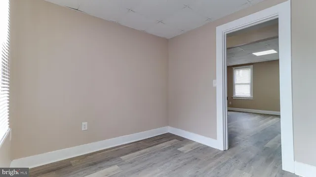 a view of an empty room with wooden floor and closet