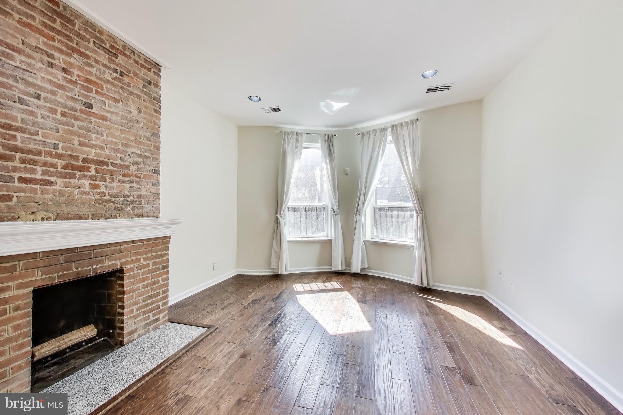 1625 S Street Northwest, Unit 1 Washington, DC 20009 - Photo 7 of 13 an empty room with wooden floor fireplace and windows