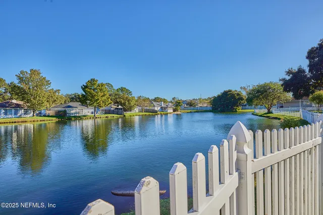 a view of a wooden chairs and lake in the background