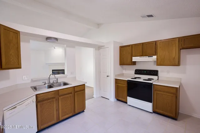 a kitchen with sink a stove and cabinets