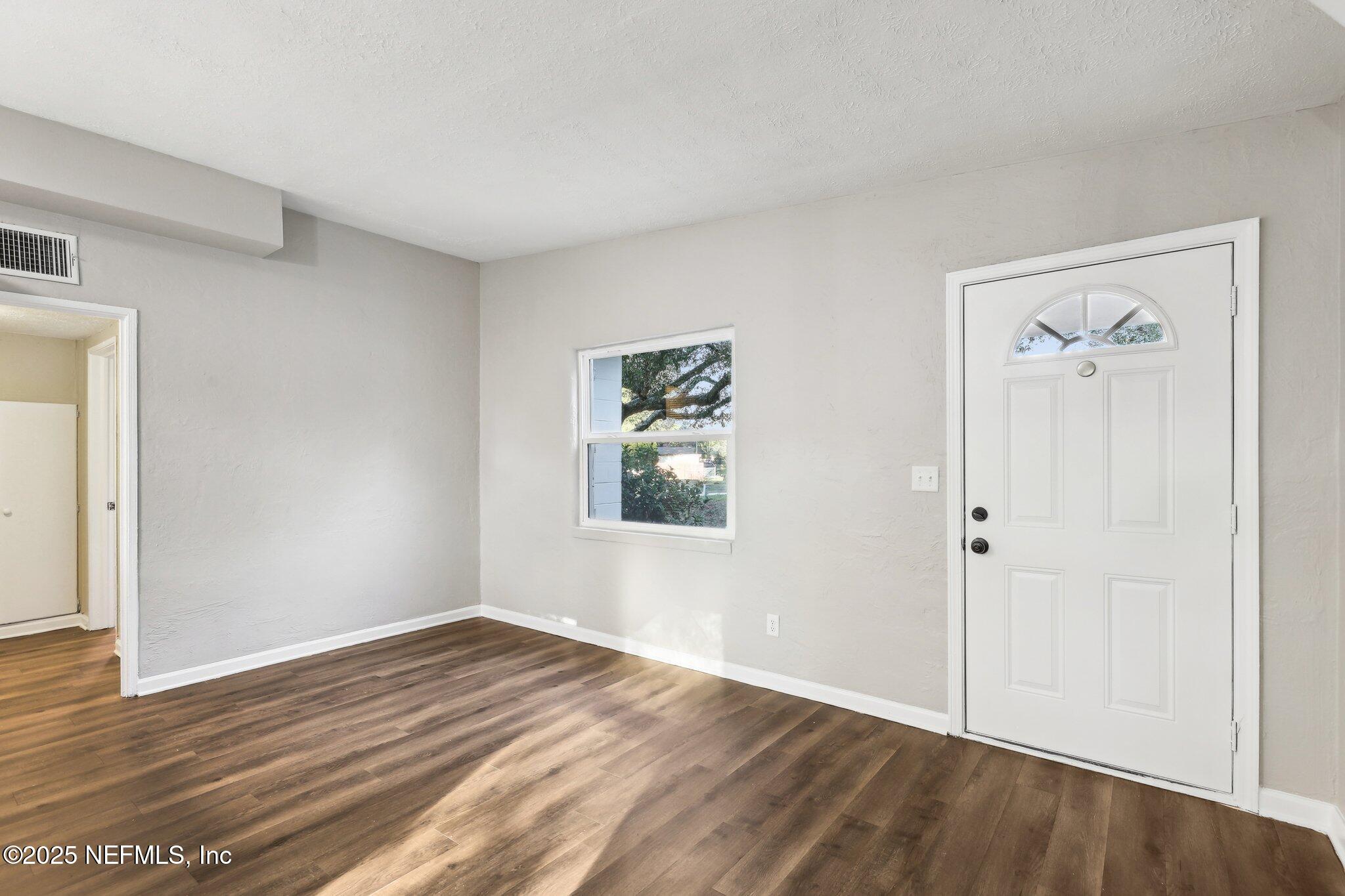 1268 King Arthur Road Jacksonville, FL 32211 - Photo 9 of 35 a view of an empty room with wooden floor and a window