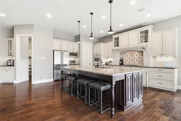 a kitchen with stainless steel appliances granite countertop a kitchen island a stove a table and a sink